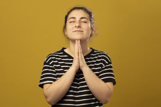 年轻女子站在画室里，手牵着手祈祷。合十礼图片下载