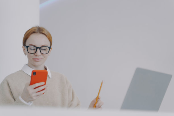 快乐的年轻女子在电话聊天有乐趣和微笑。分散学习观念。图片下载