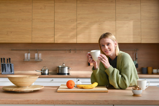 年轻女子在厨房里喝咖啡或茶图片下载