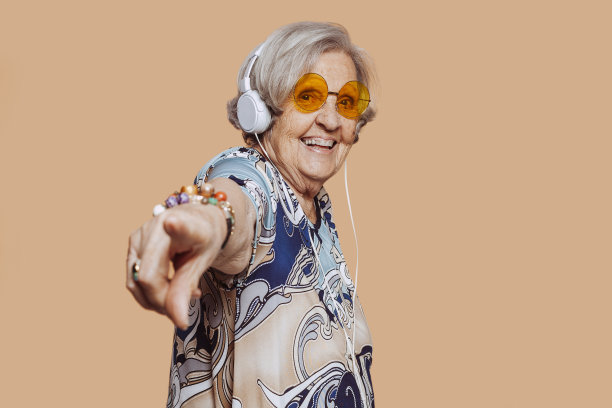 微笑的老祖母在录音室里戴着耳机听音乐图片下载