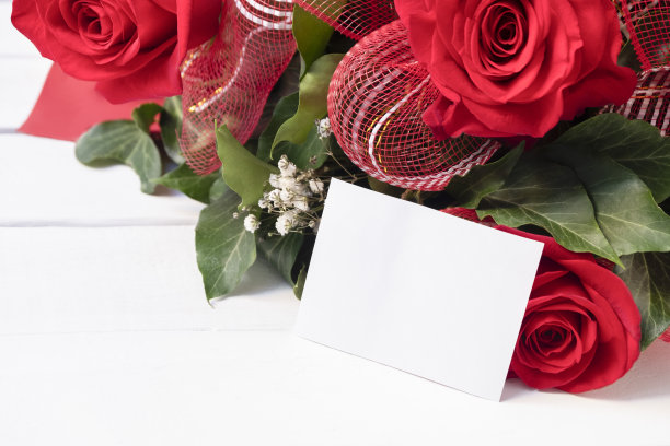 新鲜的花束新鲜的红玫瑰与空白白色卡片在白色的木制背景。节日卡片概念，文字的地方图片下载