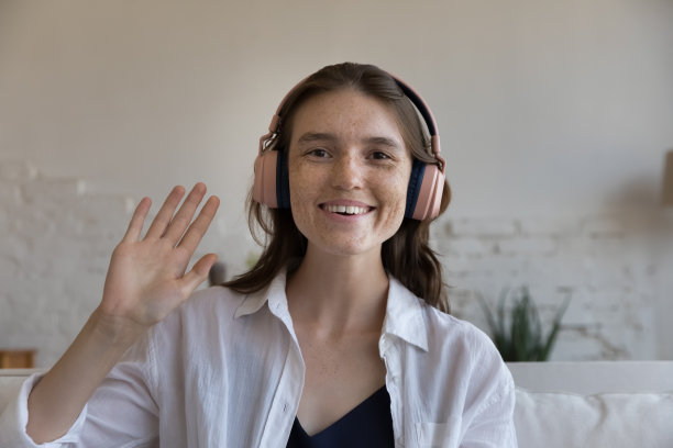 开朗的学生女生戴着大大的无线耳机挥手问好图片下载