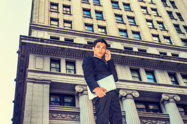 年轻的亚裔美国大学生在纽约市办公楼外打电话图片下载
