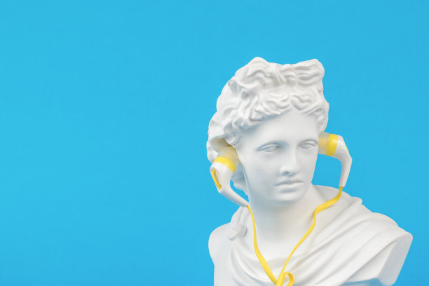 蓝色背景上戴着耳机的阿波罗石膏雕像的创意图像。最小的概念。图片下载