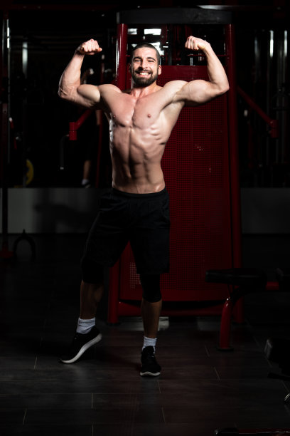 一个年轻人在体育馆的二头肌姿势图片下载
