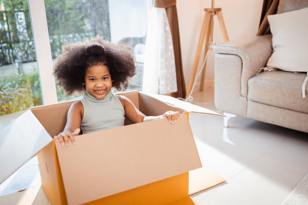 非裔美国小女孩喜欢在家里玩大纸板，周末在家活动图片下载