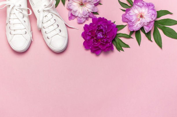 白色女性时尚运动鞋和粉红色紫色花牡丹在粉红色的背景。平面俯视图拷贝空间。女性的鞋子。时尚的白色运动鞋。时尚博客或杂志。春鞋的概念图片下载
