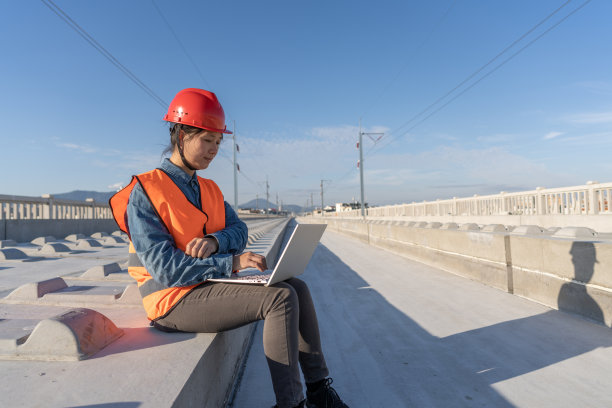 一位亚洲女工程师坐在未完工的铁路上使用电脑图片下载
