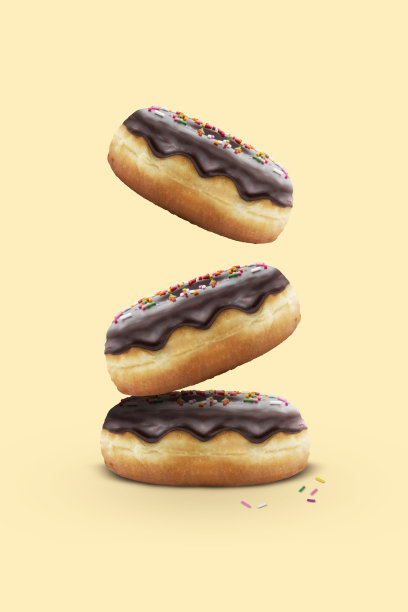 白色背景上洒满彩色糖屑的经典新鲜出炉巧克力甜甜圈图片下载