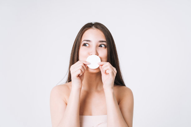 滑稽微笑的亚洲女人的美丽肖像与黑色长发棉垫清洁新鲜的皮肤脸和手在白色背景孤立，皮肤清洁和卸妆图片下载