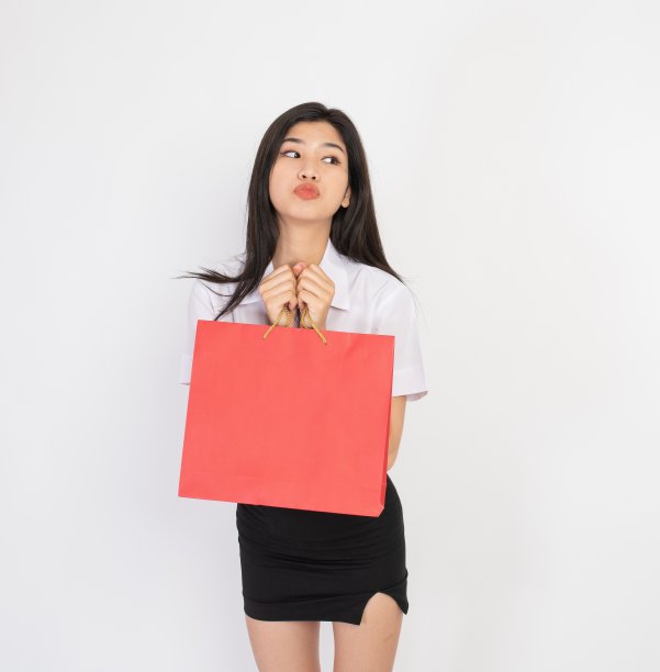 一个拿着红色购物袋的年轻亚洲女士的瞬间和表情图片下载