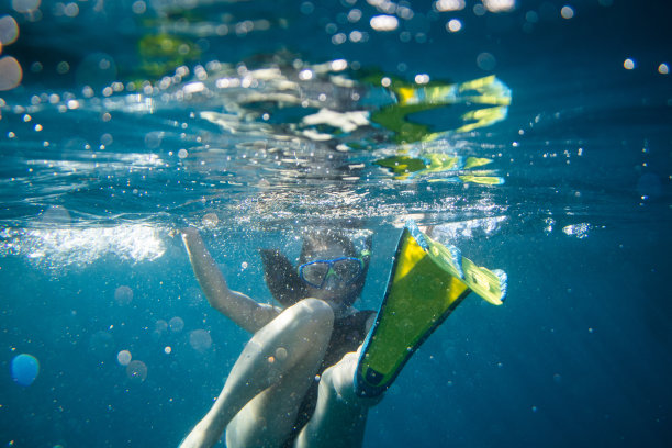 戴着泳镜和潜水脚蹼的女子在水下看着镜头图片下载