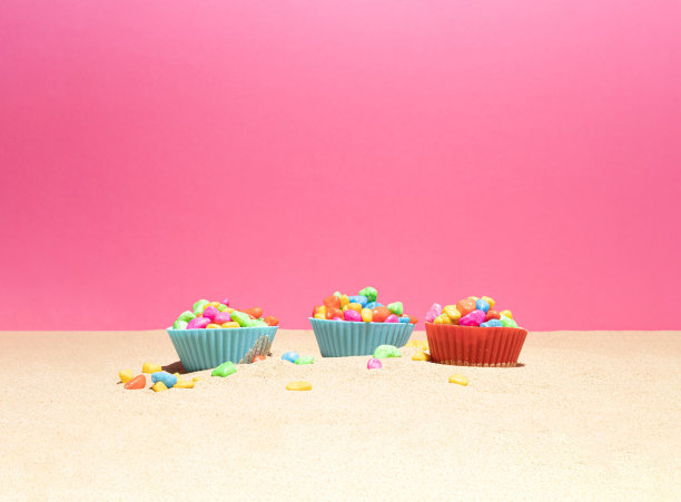 五颜六色的鹅卵石放在烘焙杯里。暑假的作文。海滩上的沙子。图片下载