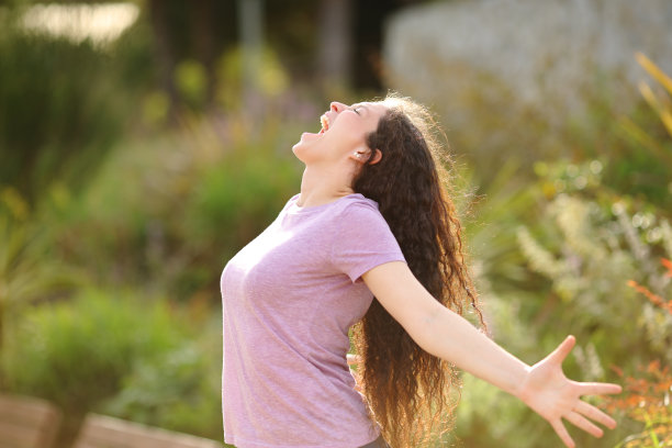 一个兴奋的女人在公园里张开双臂大喊大叫图片下载