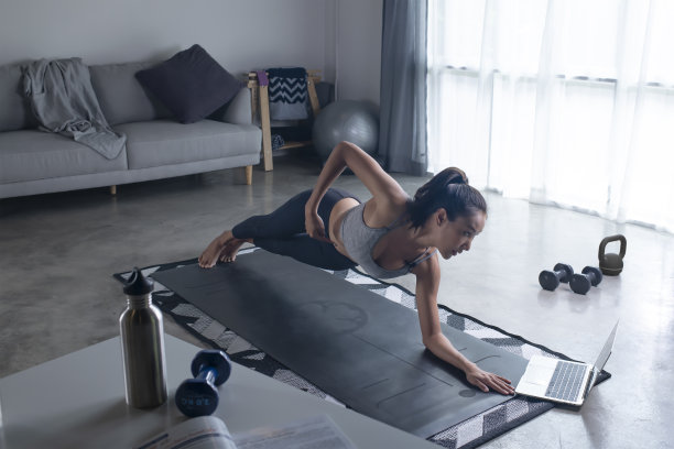 穿着运动服的女人在家锻炼，看在线健身课。图片下载