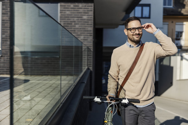 一个时髦的男人在城市街道上推着一辆自行车。图片下载