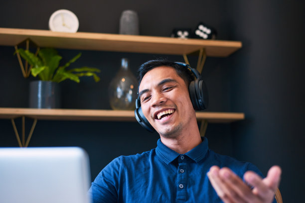 一个年轻的亚洲人在办公室的电话会议上笑着打手势图片下载