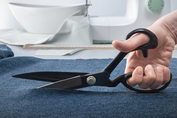 一个女人用裁缝的剪刀剪开布料。特写镜头图片下载
