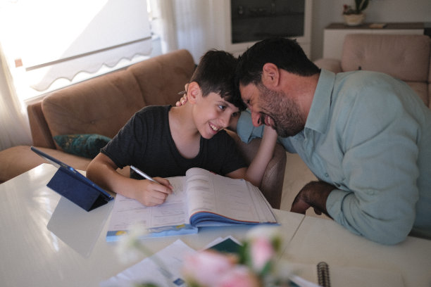 可爱的男孩正在学习电脑，爸爸在家里工作。在家教育的概念。库存图片图片下载