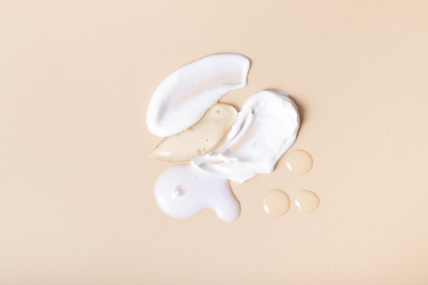 滴和涂抹化妆品顶部视图上的米色背景图片下载