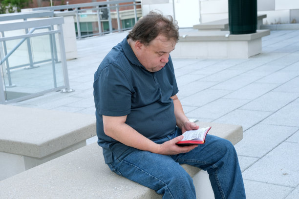 患有自闭症的成年男性坐在那里学习圣经图片下载