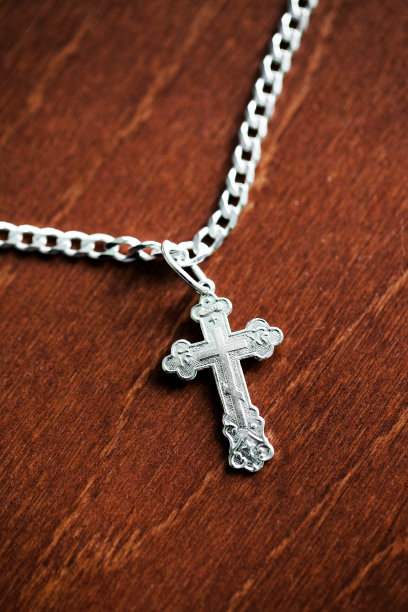 金属东正教十字架。银饰孤立在木头上。天主教的宗教象征背景。宗教附属十字架的垂直照片。图片下载