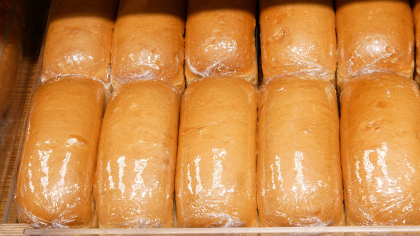 木制柜台上许多包装精美的面包的特写图片下载