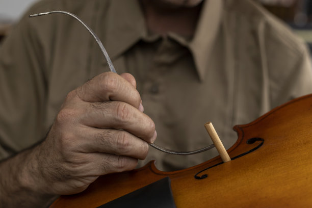 在小提琴顶部和底部之间放置音柱的拉丁美洲制琴师。弦乐器的概念图片下载