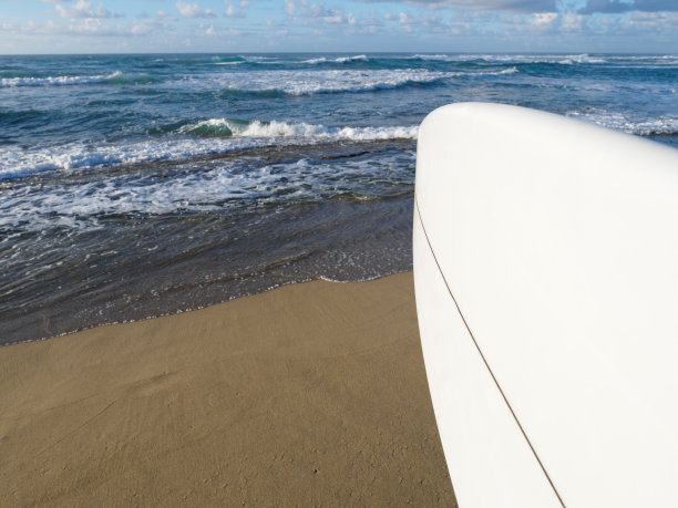 观点的看法。冲浪者站在白色冲浪板对着海洋的热带海滩上。副本的空间。图片下载