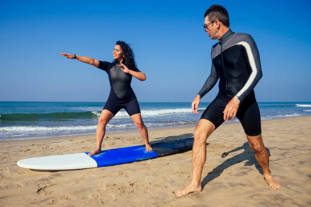 在果阿海冲浪课上，男子教练向印度女子演示如何站在冲浪板上图片下载