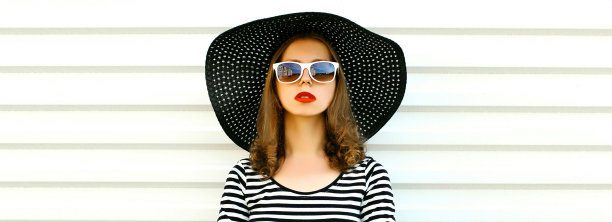 肖像美丽的年轻女子模型戴着黑色圆形夏季帽子，条纹裙在白色背景图片下载