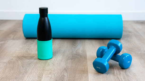 一对蓝色哑铃和可重复使用的金属水瓶在地板上做瑜伽图片下载