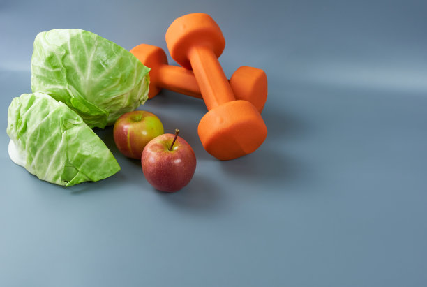 灰色背景下的新鲜卷心菜、红苹果和健身哑铃。这个概念是减肥，节食，锻炼。复制的空间。图片下载