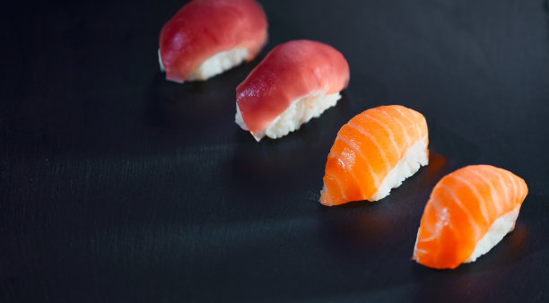 在黑色背景下准备的四个寿司片的高角度视图。图片下载