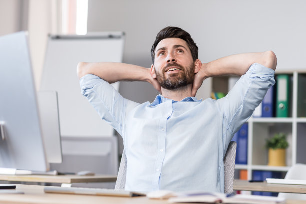 商人在办公室梦幻般的休息，把双手放在脑后，男人在做一个商业项目图片下载