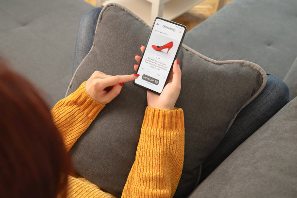 女人在家里用智能手机网购的特写。电子商务门户网站女性选鞋时手触屏后视图。图片下载