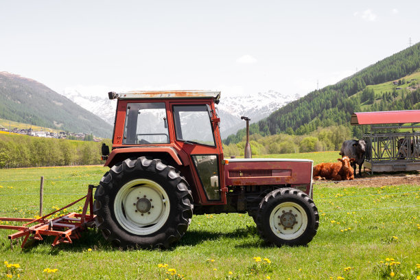 拖拉机在高山村庄的绿色草地上图片下载