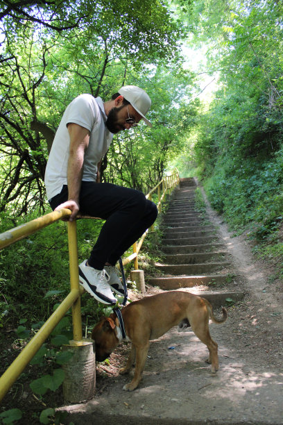 一个男人和他的狗在自然中休息的侧视图图片下载