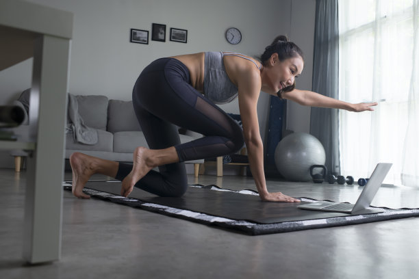 在家对着笔记本电脑锻炼的女人。图片下载