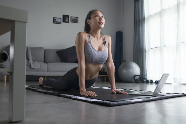 在家对着笔记本电脑锻炼的女人。图片下载