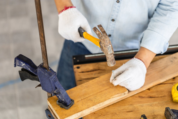 工匠在车间用锤子钉钉子，木匠在木工车间用锤子打钉子组装木材图片下载