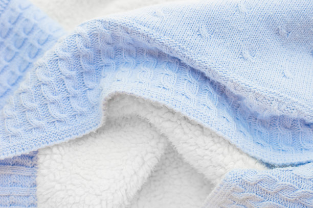 蓝色婴儿冬毯。儿童纺织品。仿羊毛质地的婴儿冬季毛毯。特写纹理蓝色针织织物与白色羔羊毛背面，俯视图图片下载