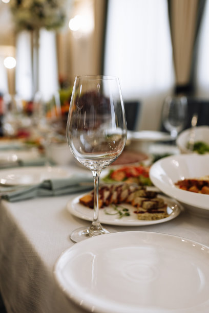 餐厅里摆放着空杯子。婚礼，装饰，庆祝，节日概念-浪漫的餐桌设置与白色桌布，盘子，水晶玻璃图片下载