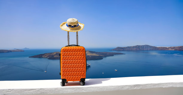 横幅的旅行概念与橙色的行李箱与帽子和风景风景的Oia镇在希腊圣托里尼岛，希腊景观为蓝天背景图片下载