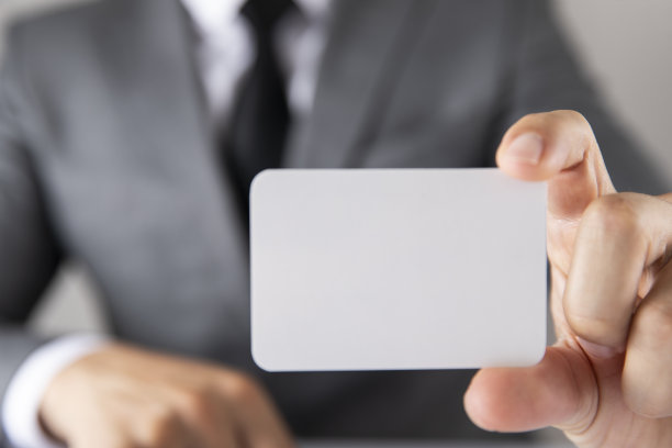 身穿灰色西装、手持空白名片的商人图片下载