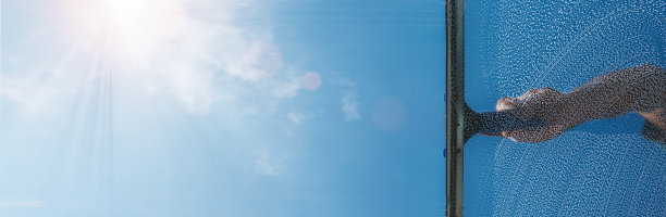 在阳光明媚的日子里，窗户清洁工用橡胶刮刀和雨刷清洁窗户图片下载