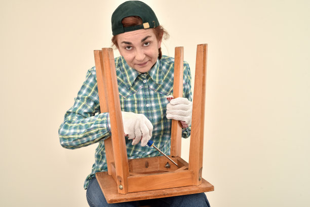 一位正在修理旧椅子的中年妇女图片下载