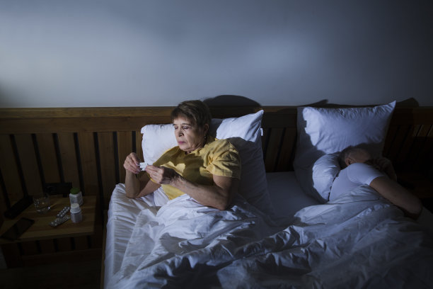 失眠。健康的睡眠。老年妇女晚上坐在床上服用安眠药图片下载