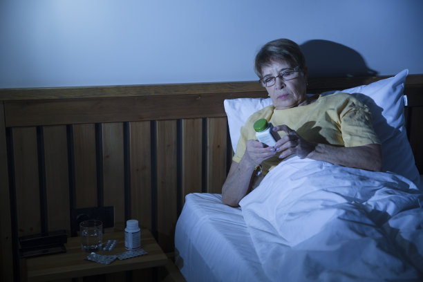 失眠。健康的睡眠。老年妇女晚上坐在床上服用安眠药图片下载