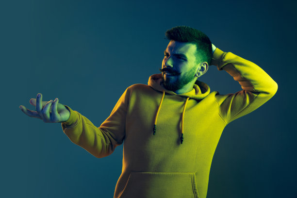 在霓虹灯的蓝色背景下，年轻感性男子的肖像显示出误解的情绪图片下载